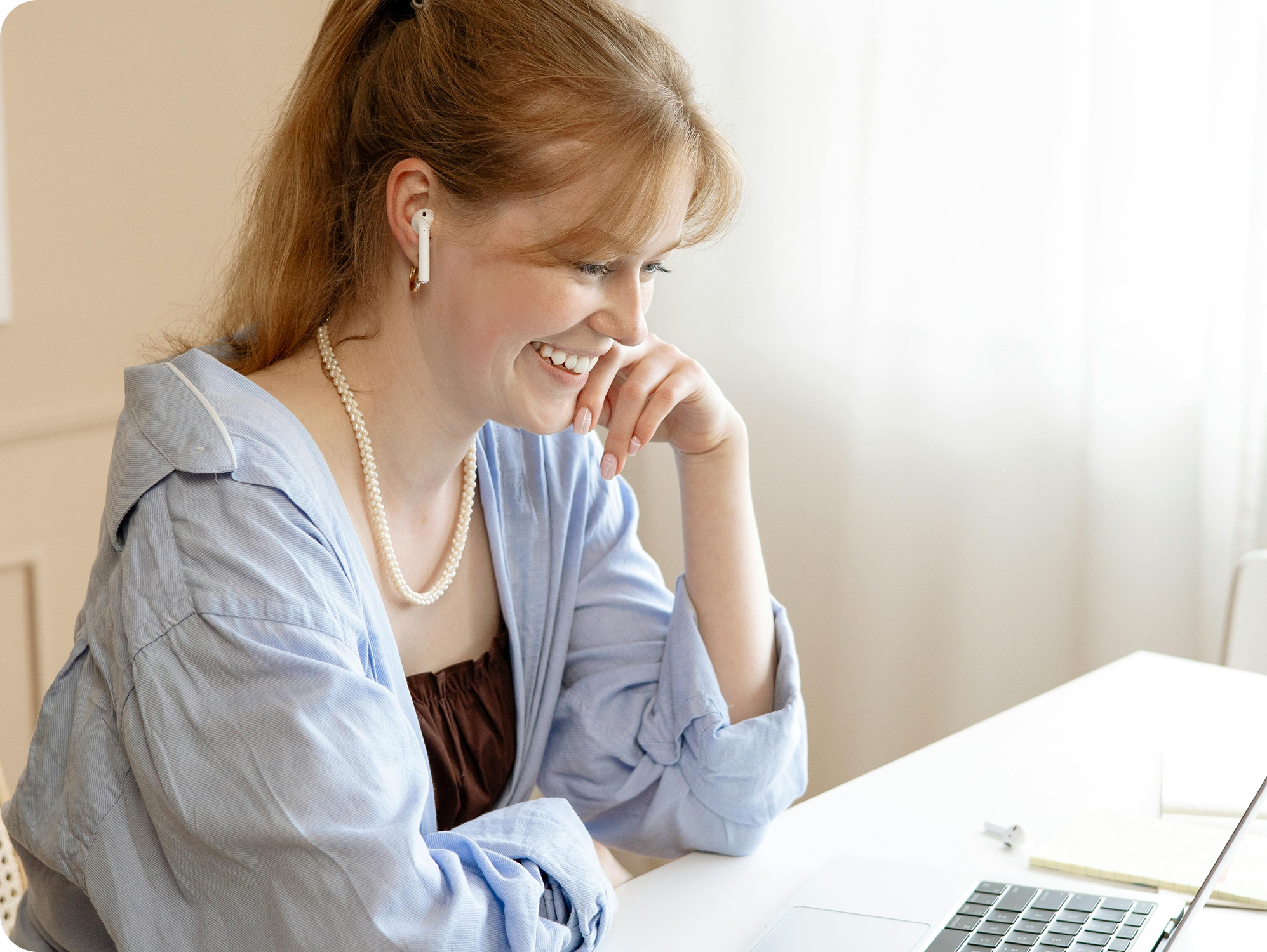 woman smiling looking down at computer with airpods in